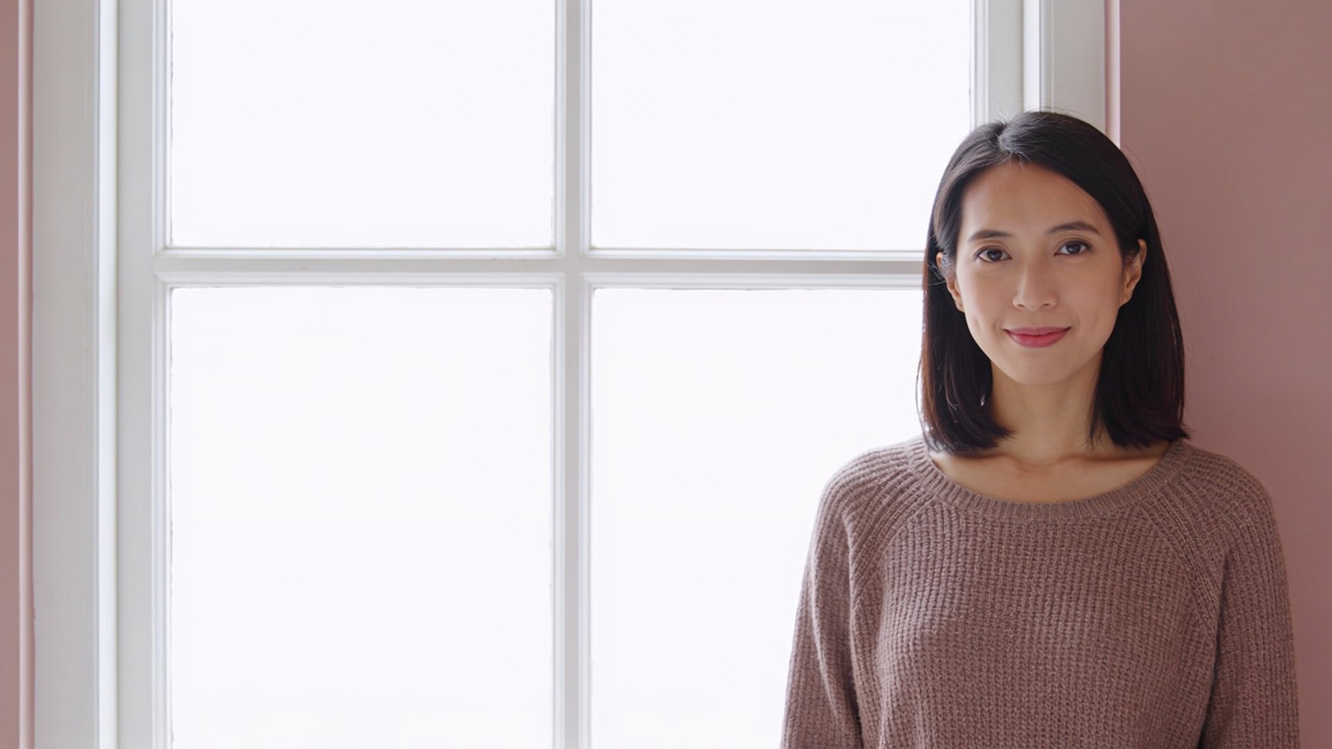 Southeast Asian woman in her thirties with clear, calm skin standing by a bright window, representing chin acne treatment at IN Eternity Clinic, Singapore