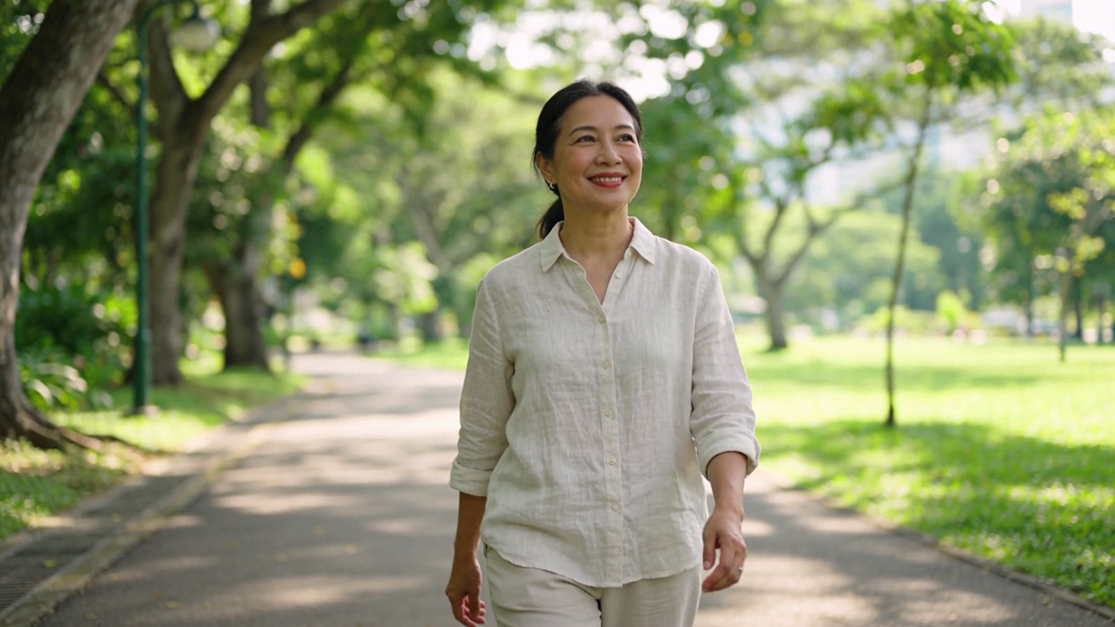 A Southeast Asian woman in her forties walking in a shaded park, her whole head and face in frame